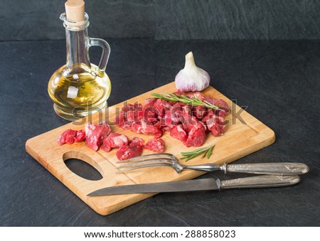 Raw beef cubes with rosemary and beefsteak spices on wooden cutting Board