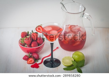 Strawberry lemonade with ice in glass on white wooden background