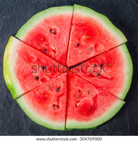 sliced watermelon on black stone background, top view