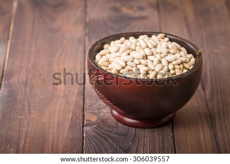 Bowl of raw white beans on wooden background