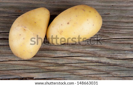 Two single potatoes on old wood