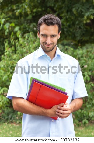 Smiling latin student with paperwork in the park