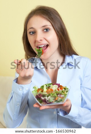 Young woman eating salad in the living room