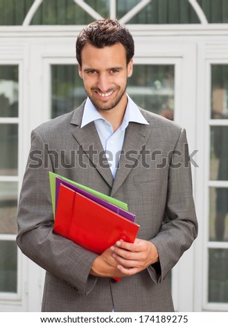 Latin businessman with paperwork in front of his office
