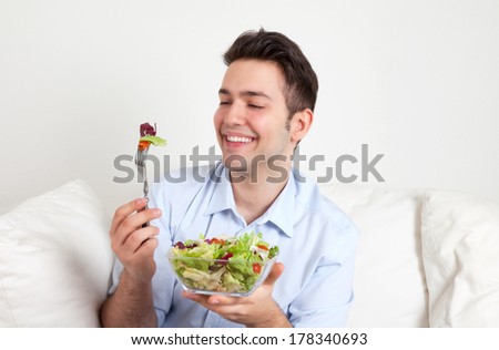 Attractive hispanic guy eating fresh green salad