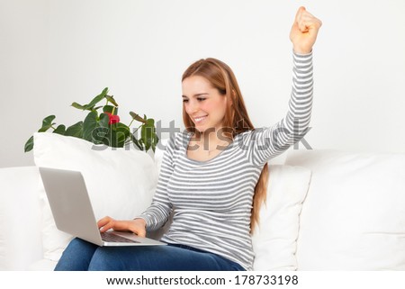 Happy young woman with notebook on a sofa