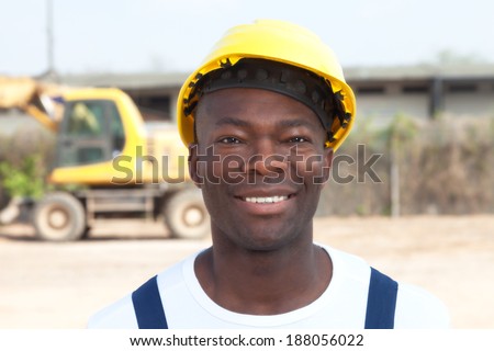Laughing african worker at construction site with excavator