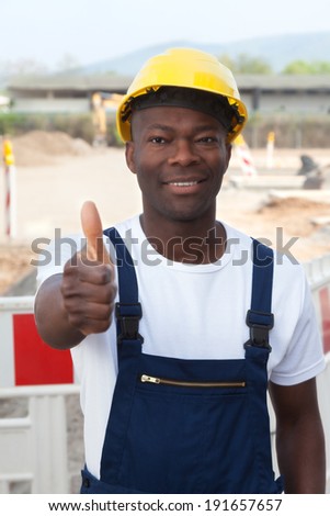 Laughing african worker at construction site showing thumb up