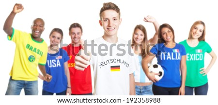 German soccer with blond hair showing thumb with other fans