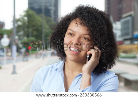 Laughing hispanic woman in the city talking at phone