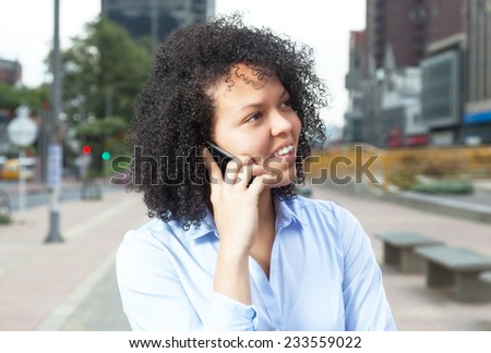 Attractive hispanic woman in the city at phone
