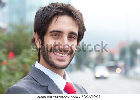 Laughing latin businessman with beard in front of his office