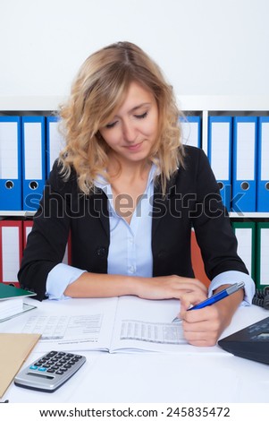 Businesswoman with curly blond hair writing note