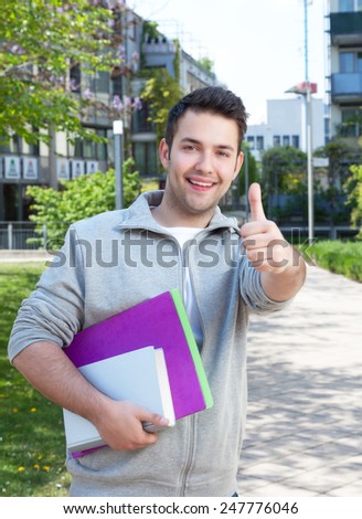 Happy hispanic student at campus showing thumb up