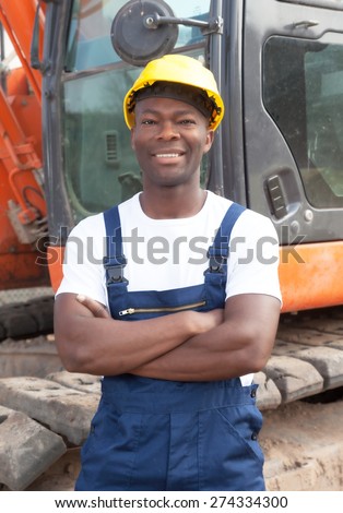 Happy african construction worker with crossed arms and red excavator