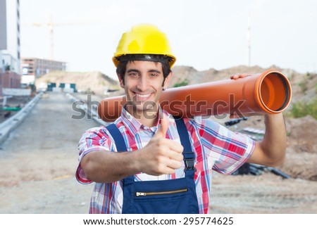 Hispanic construction worker with pipe at building site showing thumb