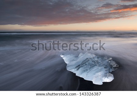 Stranded ice block on a sand beach. Jökulsarlon glacier bay, Southern Iceland.