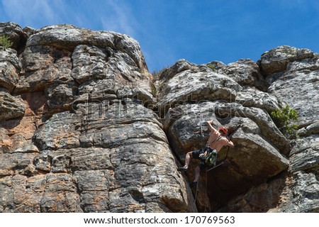 Male rock climber ascending steep climb