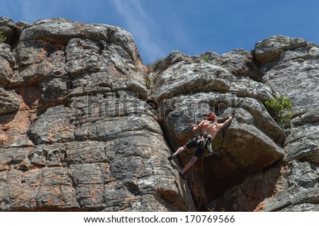 Male rock climber ascending steep climb
