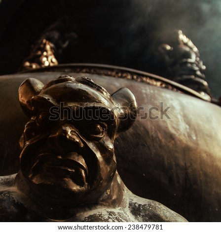 Close up of Scary Demon supporting a huge cauldron for incense burning at chinese temple Lingyin.