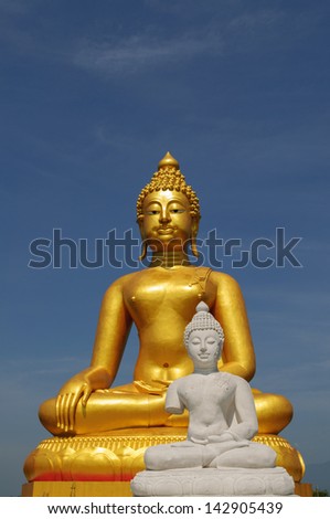 A golden and white buddha statue sits in peaceful meditation