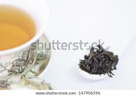 Cup of chinese tea with dry tea leaves  on white background
