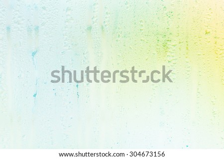 raindrops on transparent window glass - colorful abstract background