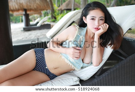 sexy beautiful asian japanese model young lady Pin Up girl posing lying on lounge chair wearing sexy jeans crop top vest and cute pant summer beachwear with attractive body sex pose no bra braless