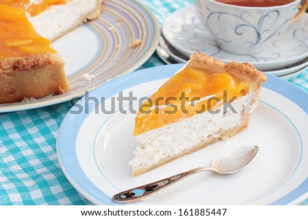 Piece of tasty peach cheesecake with agar jelly on a plate with a teaspoon