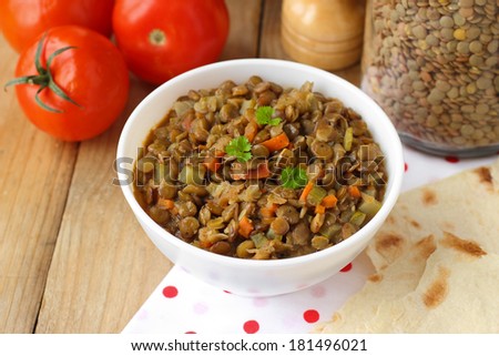 Vegan dinner - green lentils with vegetables on wooden table