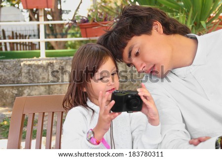 Little girl with her dad looking to the digital camera outdoors