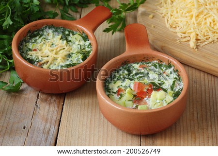 Omelette with cheese, vegetables and herbs cooked by steaming in ceramic pots