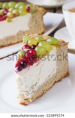 Homemade cheesecake with jelly, grapes, gooseberries, red and black currants on wooden background