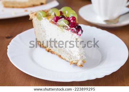 Homemade cheesecake with jelly, grapes, gooseberries, red and black currants on wooden background
