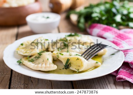 Traditional dish of Slavic cuisine. Potato-filled varenyky on a white plate on wooden table