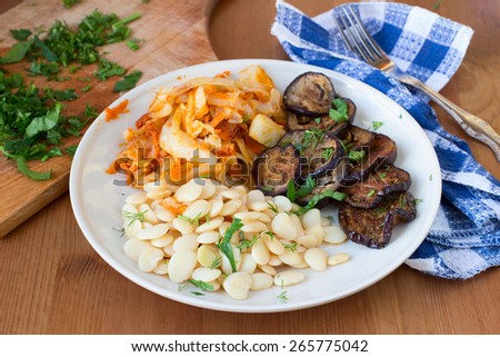 Healthy vegan food. Roasted eggplants, white beans and cooked cabbage