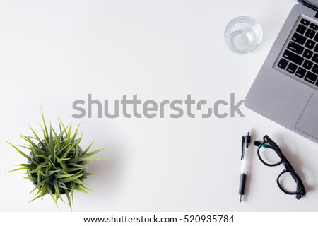 White office desk table with laptop, smartphone, and glass. Top view with copy space, flat lay.