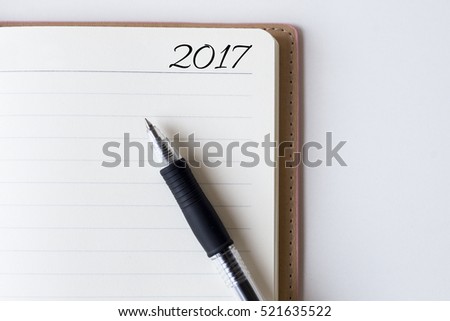 Conceptual,notebook on a white table. open diary and pen with 2017 words