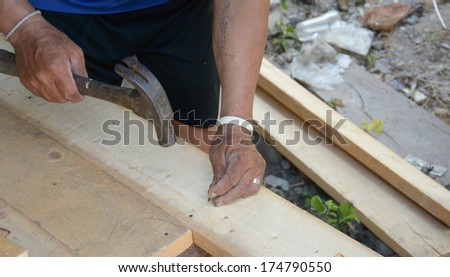 carpenter\'s hands hitting a nail on the head with old and used wood