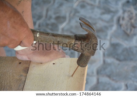 carpenter\' s hands hitting a nail on the head with old and used wood