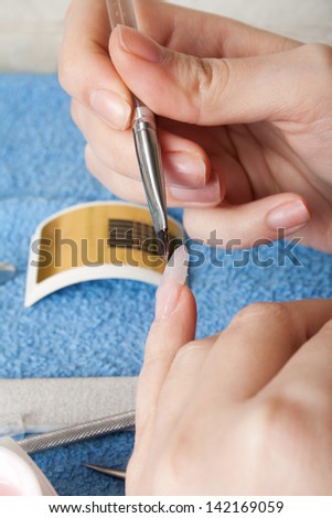 The master puts a brush a material for escalating of nails