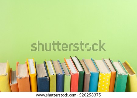 Book stack, hardback colorful books on wooden table and green background. Back to school. Copy space for text. Education concept.