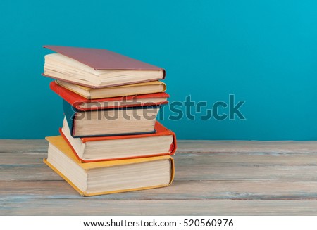 Book stack, hardback colorful books on wooden table and blue background. Back to school. Copy space for text. Education concept.