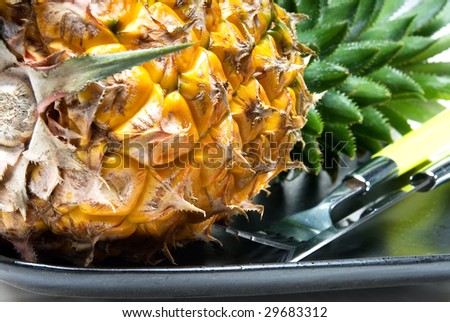 ripe vivid pineapple on a black plate with knife and fork