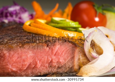 fresh juicy beef ribeye steak sliced ,with lemon and orange peel on top  and vegetable beside