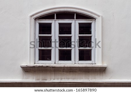 White painted wood arched window on white concrete wall