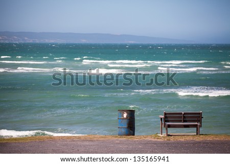 Wooden bench and iron barrel dustbin overlooking the ocean
