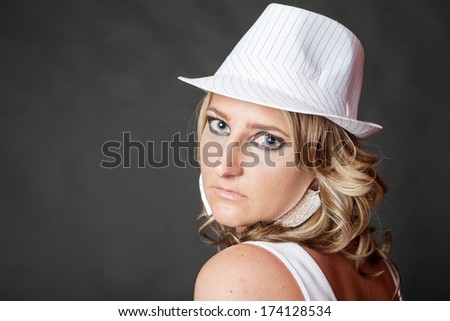 Young blonde woman with serious face wearing white pinstripe hat