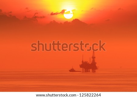 Silhouette Offshore Jack Up Drilling Rig and Boat At Sun Set Time (Yellow Tone)