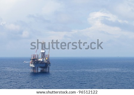Jack up drilling rig and crew boat in the middle of the coean